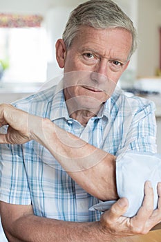 Portrait Of Mature Man Putting Ice Pack On Painful Elbow