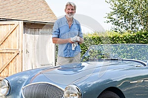 Portrait Of Mature Man Restoring Classic Sports Car Outdoors At Home