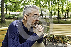 Portrait of a mature man sitting on a bench in an urban park