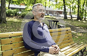 Portrait of a mature man sitting on a bench in an urban park