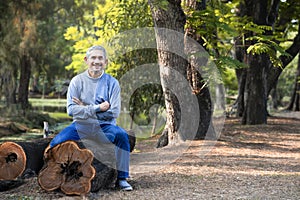 portrait mature man spend leisure time sitting on a log in the forest park