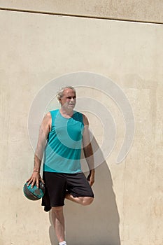 portrait of mature man on street basketball court against a wall looking outside