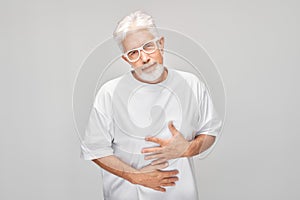 Portrait of mature man suffering from stomach pain isolated on white studio background. Intestinal and stomach