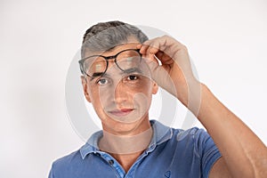 Portrait of mature man taking off eyeglasses looking at camera