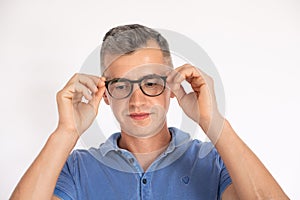 Portrait of mature man wearing blue T-shirt putting on glasses