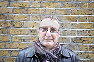 Portrait of a mature man wearing glasses with scarf against wall