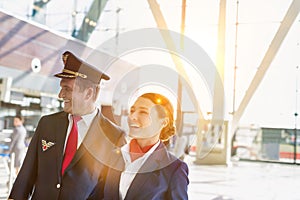 Portrait of mature pilot and attractive flight attendant walking while smiling in airport