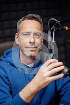 Portrait of mature radio host speaking in microphone while moderating a live show