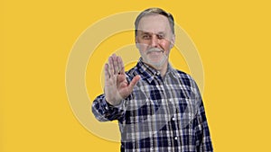 Portrait of mature senior man showing his palm as stop gesture sign.