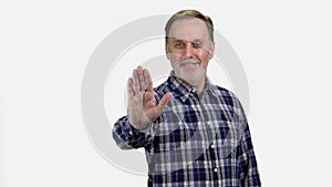 Portrait of mature senior man showing his palm as stop gesture sign.