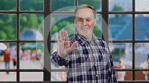 Portrait of mature senior man showing his palm as stop gesture sign.