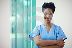 Portrait Of Mature Smiling Female Doctor Wearing Scrubs In Hospital With Copy Space