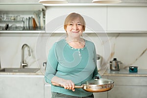 Portrait of a mature smiling woman with a frying pan in her hands