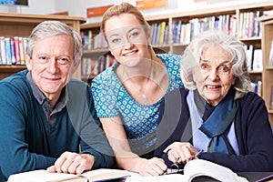 Portrait Of Mature Students Working With Teacher In Library