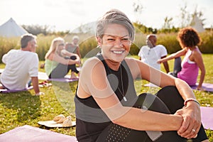 Portrait Of Mature Woman On Outdoor Yoga Retreat With Friends And Campsite In Background