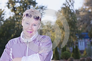 Portrait of a mature woman in sunglasses. Smiling sitting on a park bench