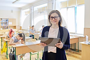 Portrait of mature woman teacher in classroom with digital tablet