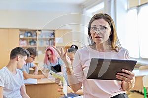 Portrait of mature woman teacher in classroom with digital tablet