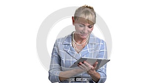 Portrait of mature woman thinking and typing on tablet pc.