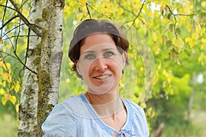Portrait of a mature woman under a birch tree photo