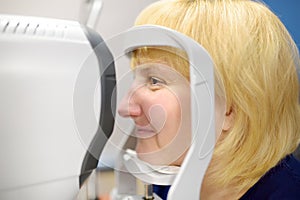 Portrait of mature woman during visit to optometrist for microscopic analysis of eyelids, sclera, conjunctiva, iris, lens, cornea photo