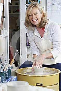 Portrait Of Mature Woman Working At Potters Wheel In Studio photo