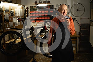 Portrait of mechanic in bicycle shop or workshop for repairs dictate voice message on phone mic. Entrepreneur, bike