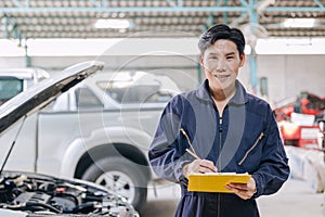 portrait mechanic engineer male happy for service fix repair broken car in garage auto shop. car insurance claim cost estimate