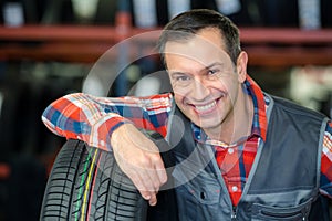 portrait mechanic in garage with new car tyre