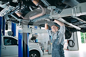 Portrait of a mechanic repairing a lifted car.