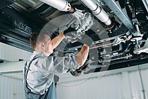 Portrait of a mechanic repairing a lifted car.