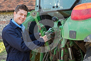 Portrait Of Mechanic Repairing Tractor On Farm