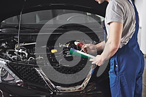 Portrait of a mechanic at work in his garage - car service, repair, maintenance and people concept