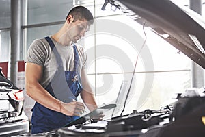 Portrait of a mechanic at work in his garage - car service, repair, maintenance and people concept
