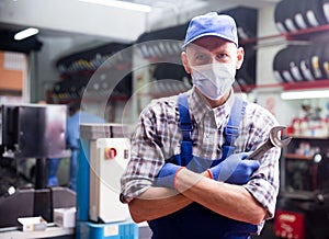 Portrait of mechanician in mask posing at auto service