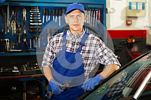 Portrait of mechanician posing near car at auto service