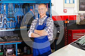 Portrait of mechanician posing near car at auto service