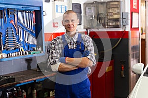 Portrait of mechanician posing near car at auto service