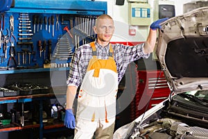 Portrait of mechanician posing near car at auto service