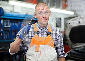 Portrait of mechanician posing near car at auto service