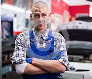 Portrait of mechanician posing near car at auto service