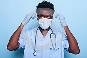 Portrait of medical assistant putting mask on face for protection