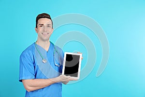 Portrait of medical assistant with stethoscope and tablet on color background