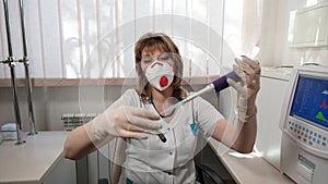 Portrait of a medical laboratory technician in respirator with tube in a hand