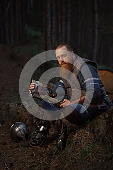 Portrait of medieval red-haired viking warrior with beard with an ax in forest