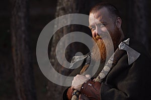 Portrait of medieval red-haired viking warrior with beard with two axes