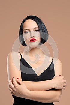 Portrait of melancholic lady in dress with straps. Studio shot on beige background