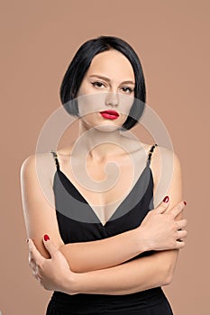 Portrait of melancholic lady in dress with straps. Studio shot on beige background