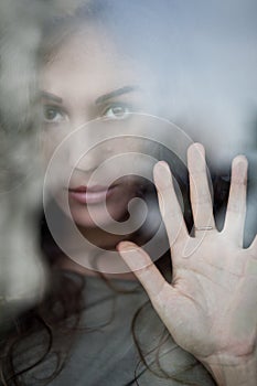 Portrait of melancholic woman behind the window