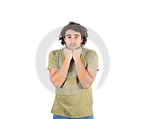 Portrait of melancholic young man, long curly hair style, keeps fists under chin, looking confused and dissatisfied. Person